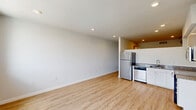 Located at 2120 E York St in Philadelphia's vibrant Fishtown neighborhood, this modern unit offers a thoughtfully designed single-floor layout with clean, contemporary finishes throughout. Light-toned hardwood flooring flows seamlessly across the open-concept living and kitchen area, creating a bright and cohesive aesthetic. Recessed lighting illuminates the space, while large windows allow natural light to pour in and provide views of the surrounding neighborhood. An exposed industrial-style ductwork element adds a stylish urban touch to the living area. The kitchen is outfitted with stainless steel appliances — including a refrigerator, range, microwave, and dishwasher — complemented by white cabinetry and granite countertops. A hallway featuring a sleek barn door leads to the additional rooms, including a private bedroom with recessed lighting and a clean, neutral palette. The full bathroom is well-appointed with a granite-topped vanity, a large mirror, white subway tile tub surround with built-in shelving, and large-format tile flooring. A utility room provides practical storage and functional support. The overall ambiance is fresh, modern, and move-in ready, ideal for those seeking contemporary urban living in one of Philadelphia's most sought-after neighborhoods.