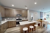 Located at 110 Goldsborough Dr in Bayonne, NJ, this well-appointed three-bedroom, two-bathroom residence offers a thoughtfully designed single-floor layout with modern finishes throughout. Light wood-look flooring flows seamlessly across the hallways and main living areas, creating a warm and cohesive aesthetic.

The open-concept kitchen is a standout feature, equipped with stainless steel appliances including a gas range, microwave, and full-size refrigerator. Woodgrain flat-front cabinetry reaches toward the ceiling for generous storage, while a central island with a white countertop and built-in sink provides additional prep space and casual seating.

The adjoining living room is bright and inviting, with recessed lighting and neutral walls that lend a clean, contemporary feel. A well-proportioned hallway connects the three bedrooms, each offering comfortable dimensions. The spacious primary bedroom receives natural light from a large window with exterior views. The additional bedrooms share similarly soft, neutral tones and ample room.

The two bathrooms are finished with care — one features a glass-enclosed walk-in shower with tiled surround and a wood-toned vanity, while the second includes a full soaking tub with a tiled shower surround. Both bathrooms continue the wood-look flooring found throughout the residence, tying the design together cohesively.