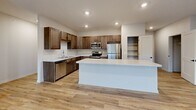 Located at 1220 W Highland Blvd in Lincoln, Nebraska, this well-designed two-story home offers 2 bedrooms, 2 bathrooms, an attached garage, and a thoughtful layout across two levels. The main living floor hosts the majority of the home's living space, beginning with a bright, open living room featuring light hardwood-style flooring, recessed lighting, and a sliding glass door that opens to a private balcony, allowing abundant natural light and outdoor views. The kitchen is a standout feature, showcasing rich dark cabinetry, quartz countertops, stainless steel appliances, and a central island — ideal for both cooking and entertaining. A dedicated laundry room with built-in shelving and full-size washer and dryer hookups adds everyday convenience. Both bedrooms are carpeted and include ceiling fans and windows with neighborhood views. The primary bedroom is a comfortable size and benefits from a private bathroom with warm wood-toned cabinetry and light flooring, as well as a walk-in closet with built-in shelving and hanging rods. Three closets throughout provide generous storage. The lower level houses the attached garage with a concrete floor and interior access. Clean neutral finishes, black hardware accents, and consistent flooring choices throughout give the home a cohesive, modern aesthetic.
