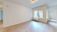 Located at 4010 196th St SW in Lynnwood, WA, this thoughtfully designed 3-bedroom, 2-bathroom single-floor unit offers a clean, modern aesthetic throughout. Light wood-tone flooring runs continuously across all rooms, creating a warm and cohesive feel. The open kitchen is a standout feature, equipped with sleek flat-front cabinetry in a two-tone taupe and natural wood finish, white quartz countertops, under-cabinet lighting, and a full suite of stainless steel appliances including a French door refrigerator, electric range, built-in microwave, and dishwasher. The bedrooms are bright and airy, with crisp white walls and ample closet space; one room features a modern sliding barn door, while others include sliding panel closets. A window unit provides individual climate control in the primary bedroom, which receives natural light from an outdoor-facing window. The two bathrooms are finished in a consistent, neutral palette — one features a soaking tub and shower combination with white subway tile surround and brushed nickel fixtures, while the other offers a vanity with warm wood cabinetry and an illuminated mirror. A connecting hallway ties the layout together efficiently, making this a practical and stylish home.