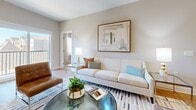 This thoughtfully designed single-story residence in Columbia, Tennessee, offers a seamless open-concept layout connecting the living room, dining area, and kitchen. The kitchen is outfitted with white shaker cabinetry, stainless steel appliances including a refrigerator, range, microwave, and dishwasher, white quartz countertops, and pendant lighting above the sink peninsula. Light wood-look flooring flows throughout the main living areas, contributing to a bright, cohesive aesthetic.

The living room features sliding glass door access to an outdoor area, filling the space with natural light. The primary bedroom is generously sized with plush carpet, a ceiling fan, and windows with shutters, adjoined by an en-suite bathroom. The second bedroom is equally comfortable with similar finishes and a ceiling fan. Three bathrooms are distributed throughout, each featuring tub-shower combinations with white tile surrounds, clean vanities, and built-in shelving in select units.

A dedicated laundry room accommodates full-size washer and dryer units with overhead shelving. The neutral color palette and modern fixtures throughout create a polished, move-in-ready environment.