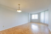 Located at 30 Elm Dr E in Mississauga, Ontario, this one-bedroom, one-bathroom unit offers a practical and well-organized layout across a single floor. Warm parquet flooring flows throughout the main living and bedroom areas, adding a classic character to the space.

The open dining and living area is bright and functional, benefiting from natural light filtering through windows dressed with vertical blinds. A pass-through opening connects this space seamlessly to the kitchen, which features white cabinetry, dark laminate countertops, a double sink, and a white electric range — providing a clean, efficient workspace with tile flooring.

The bedroom is a comfortable size, accommodating standard furnishings with ease. It features the same parquet flooring as the main living area and receives natural light through a window with an outdoor view of greenery and surrounding buildings.

The bathroom is fitted with a full-size soaker tub and shower combination, surrounded by classic white square wall tiles, along with standard fixtures. Multiple hallways connect the rooms, offering good flow throughout the unit.

The textured ceilings and neutral wall tones throughout maintain a clean, understated aesthetic, making this a practical and move-in ready space in a convenient Mississauga location.