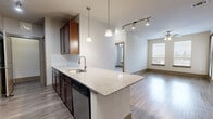 Located in Houston's desirable 77007 zip code, this single-floor residence at 155 Birdsall Street offers a well-designed layout with modern finishes throughout. The open-concept kitchen serves as the heart of the space, showcasing rich dark-wood cabinetry, granite countertops, a subway tile backsplash, and a large center island with a stainless steel sink and pendant lighting overhead. Stainless steel appliances — including a refrigerator, range, microwave, and dishwasher — complete the chef-friendly setup. Track lighting adds a contemporary touch to the kitchen and living area, which flows seamlessly across durable wood-style plank flooring. The entry features a glass-paneled front door fitted with blinds for privacy and natural light control. Bedrooms are carpeted for comfort and include ample closet space, with the primary bedroom offering access to an en-suite bathroom and a walk-in closet with built-in shelving. The bathroom features tile flooring, a granite-topped vanity with dark wood cabinetry, and a full soaking tub with white subway tile surround. Neutral wall tones, panel-style interior doors with brushed nickel hardware, and large windows with horizontal blinds create a clean, cohesive aesthetic throughout the entire space.