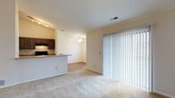 Located at 421 Lancaster Ave in Reynoldsburg, Ohio, this single-floor unit offers a practical and comfortable layout designed for everyday living. The open-concept living and dining area is finished with neutral-toned carpet and anchored by a sliding glass door with vertical blinds that fills the space with natural light. A peninsula-style pass-through kitchen connects seamlessly to the living area, featuring dark cabinetry, a black gas range, a refrigerator, a dishwasher, and a track lighting system overhead. The kitchen also includes durable wood-look flooring, providing a clean contrast to the carpeted living spaces. A ceiling fan with a light fixture is present in the dining area, adding both comfort and functionality. The bedrooms are generously sized, each carpeted and equipped with ceiling fans and windows fitted with blinds that allow for natural light and outdoor views of the surrounding neighborhood. The bathroom features a full-size soaking tub and shower combination with chrome fixtures and towel bars, set against clean white surroundings. Throughout the unit, the neutral color palette and simple finishes create a bright, move-in-ready environment well-suited for a range of living arrangements.