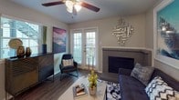 This single-story, one-bedroom, one-bathroom residence is thoughtfully designed to maximize functionality and comfort. The living room serves as the focal point of the home, featuring a tile-surround fireplace, wood-style flooring, and a ceiling fan with light fixture. French doors flood the space with natural light while providing outdoor access, and neutral gray walls create a versatile backdrop throughout.

The galley-style kitchen is efficiently arranged with black appliances, including a refrigerator, electric range, and dishwasher, complemented by wood-toned cabinetry and light countertops. A window above the sink allows natural light in, and wood-style flooring continues through the space. A dedicated pantry or storage closet adds practical utility.

The bedroom offers a carpeted floor for added comfort, a window with outdoor views, and a textured ceiling. The room comfortably accommodates a full-sized bed alongside additional furnishings.

The bathroom includes a full tub-shower combination with a curtain rod, neutral tile surround, and a toilet, finished with classic fixtures and a clean, simple design. The overall layout of this residence provides an efficient use of space with a cohesive, contemporary aesthetic throughout.