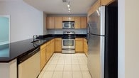 This single-floor residence offers a thoughtfully designed layout with a variety of functional spaces. The open living and dining area is a standout feature, showcasing warm hardwood flooring and track lighting overhead. Large sliding doors along one wall invite natural light and provide access to an outdoor balcony, enhancing the sense of openness throughout. The kitchen is well-equipped, featuring light maple cabinetry, dark granite countertops, stainless steel appliances including a refrigerator, range, and microwave, and clean tile flooring. A half-bath near the entry provides convenient access for guests, finished with tile flooring and a pedestal sink.

The bedrooms are carpeted for comfort, with neutral-toned walls and practical built-in niches in at least one room. Each bedroom benefits from private or nearby bathroom access. The bathrooms are consistently appointed with maple vanity cabinetry, dark granite countertops, tile flooring, and well-lit mirrors. The primary bathroom features a dual-sink vanity, offering additional functionality. Throughout, the design maintains a cohesive, contemporary aesthetic with neutral tones and clean architectural lines.