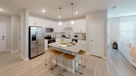 This thoughtfully designed single-floor residence offers a cohesive blend of modern finishes and comfortable living spaces throughout. The kitchen serves as a central highlight, featuring crisp white cabinetry, quartz-style countertops, stainless steel appliances, and a central island with seating — all illuminated by pendant lighting and recessed fixtures above light wood-look flooring.

The space includes multiple bedrooms, each finished with soft carpeting, ceiling fans, and generous natural light from large windows with blinds. The primary bedroom connects to a walk-in closet and is complemented by a spacious en-suite bathroom. This bathroom showcases a long vanity with an undermount sink, a glass-enclosed walk-in shower with marble-style tile surround, and light wood-look flooring. A secondary bathroom mirrors the same clean aesthetic, featuring a single vanity and a tub-shower combination.

Additional rooms include a versatile flex space ideal for a home office or sitting area, accented by neutral tones and abundant natural light. Throughout the residence, a calming coastal-inspired palette of soft grays, warm beiges, and whites creates a serene and inviting ambiance. The open floor plan, as seen in the overhead dollhouse view, ensures a functional and well-connected layout.