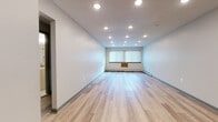 Located at 1150 S Main St in Middletown, Connecticut, this thoughtfully updated single-floor unit offers a clean, modern aesthetic throughout. The open main living area is anchored by light-toned hardwood-style flooring and bright white walls, illuminated by recessed lighting that creates an even, welcoming glow. Windows along the exterior walls allow natural light to filter in, enhancing the airy feel of the space. Baseboard heating runs along the perimeter, providing efficient climate control.

The kitchenette area is well-appointed with slate-gray cabinetry, granite-look countertops, a stainless steel sink, and a mosaic tile backsplash featuring warm earth tones — a refined detail that adds character to the functional space.

The bedroom features rich, medium-toned hardwood-style flooring, a large window that draws in natural light, and a textured ceiling. A secondary room with similar flooring offers additional flexible space, serviced by a gray entry door.

The bathroom is finished in crisp white tile and features a full tub and shower combination equipped with grab bars for accessibility, a mirrored medicine cabinet, and a streamlined vanity with clean hardware. The overall design of the unit balances modern finishes with practical, accessible features throughout.