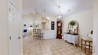 Located at 68 Richards Dr in Tifton, Georgia, this well-appointed single-story home offers a comfortable and cohesive living experience across two bedrooms and three bathrooms. The open-concept main living area immediately impresses with soaring vaulted ceilings and a lantern-style pendant light, creating an airy, welcoming atmosphere. The living room features plush carpeting, a ceiling fan, and an open sightline into the dining room, which is bathed in natural light from large windows dressed with sheer curtains and showcases warm hardwood flooring. The kitchen is defined by white cabinetry, a stainless steel range, and a peninsula breakfast bar with seating — ideal for casual dining or entertaining. A pass-through design connects the kitchen seamlessly to the main living areas. The primary bedroom offers generous proportions, soft carpet, a ceiling fan, and direct access to its own en suite bathroom, which features a single-sink vanity with warm countertops and tile flooring. An additional bedroom provides comfortable accommodations. Throughout the home, warm cream-toned walls lend a neutral, light-filled backdrop. The layout, captured clearly in the dollhouse view, reveals a well-organized floor plan with two hallways providing easy access to all rooms.