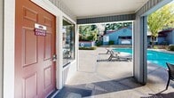 Located at 7849 Sunrise Blvd in Citrus Heights, California, this single-level community amenity space offers a well-appointed outdoor retreat designed for recreation and relaxation. The centerpiece of the property is a generously sized swimming pool with clear, blue water, accessible via stainless steel entry rails and surrounded by a broad concrete pool deck. Lounge chairs and seating areas are thoughtfully arranged around the pool, providing ample space for sunbathing and leisure.

A covered patio area adjacent to the pool offers shade and shelter, furnished with an outdoor dining table and chairs — ideal for al fresco gatherings. The structure features a distinctive architectural design with vertical board-and-batten gray siding, red-accented rooflines, and tall pitched gable windows that allow natural light to filter through. A dedicated fitness center is conveniently accessible directly from the covered patio area.

The space is enclosed by fencing for privacy and security, while mature evergreen and deciduous trees frame the perimeter, creating a lush, park-like atmosphere and providing natural shade throughout the day. The surrounding landscaping includes well-maintained hedges and shrubs that enhance the overall aesthetic. This community amenity space combines functional outdoor facilities with an inviting, tree-canopied environment.