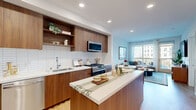 Located at 12520 Camino Del Sur in San Diego, CA, this well-designed two-bedroom, one-bathroom residence offers a thoughtfully organized single-level floor plan. The open-concept living area seamlessly connects the kitchen, dining, and living spaces, creating an efficient and welcoming environment. The modern kitchen is a standout feature, showcasing rich walnut-toned cabinetry, open shelving, a white subway tile backsplash, a central island with quartz countertops, and a full suite of stainless steel appliances. Light wood flooring runs throughout, enhancing the bright, airy atmosphere created by recessed lighting and large windows. The living room opens to a private balcony through floor-to-ceiling glass doors, filling the space with natural light and providing outdoor views. The primary bedroom is a comfortable retreat with a large window that further brings in natural light. The full bathroom features a walnut vanity, white countertop, and a soaking tub with shower combination. A clean hallway with two built-in closets connects the bedrooms and bathroom, while an in-unit laundry area adds everyday convenience. The overall design balances modern finishes with a warm, residential ambiance.