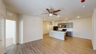 This single-story, 2-bedroom, 2-bathroom residence in Denham Springs, Louisiana is designed with a clean, modern aesthetic and a functional open-concept layout. The living and kitchen areas flow seamlessly together, anchored by wood-look plank flooring and neutral wall tones that create a bright, welcoming atmosphere. Ceiling fans provide comfort in the main living area and bedrooms.

The kitchen is a standout feature, showcasing gray cabinetry with brushed nickel hardware, white countertops, a subway tile backsplash, and a central island with a built-in sink and pendant lighting above. Black appliances, including a refrigerator, electric range, and microwave, complete the well-equipped space. A louvered-door closet nearby provides convenient in-unit laundry access.

Both bedrooms are carpeted for comfort and include ceiling fans and ample natural light from windows with blinds. The primary bedroom features a walk-in closet, while the en-suite bathroom offers a dual-sink vanity with gray cabinetry, white countertops, and a tub-shower combination. The second bathroom mirrors the same modern finishes. A glass-paneled exterior door in one room provides additional natural light and outdoor access, enhancing the overall sense of openness throughout the home.