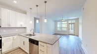 Located at 2705 Haverford Place in Charlotte, NC, this well-appointed single-floor residence offers three bedrooms and three bathrooms with a thoughtfully designed open-concept layout. The kitchen serves as the centerpiece of the living area, showcasing white shaker cabinetry, granite countertops, a subway tile backsplash, stainless steel appliances including a refrigerator with ice maker, range, microwave, and dishwasher, and a peninsula with pendant lighting that overlooks the living room. The living area features wood-style flooring, a ceiling fan, and large windows and a glass door that invite abundant natural light and provide outdoor access. A clean, bright hallway connects the main living space to the bedrooms, with recessed lighting and continued wood-style flooring. The bedrooms feature plush carpet, ceiling fans, and generous windows. Two closets provide ample storage, including a walk-in closet with built-in shelving and hanging rods. The bathrooms are finished with granite vanity tops, gray cabinetry, and tiled tub-shower combinations. The neutral color palette and modern finishes throughout create a bright, cohesive ambiance suited for comfortable everyday living.