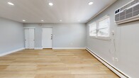 Located at 1008 E Lycoming St in Philadelphia's 19124 neighborhood, this thoughtfully updated 2-bedroom, 1-bathroom unit offers a clean, modern aesthetic throughout its single-floor layout. Light wood plank flooring runs continuously throughout the space, creating a cohesive and airy feel.

The open-concept kitchen and living area serves as the heart of the unit. The kitchen is a standout feature, showcasing white shaker cabinets, stainless steel appliances including a gas range and microwave, a bold blue hexagonal tile backsplash, and a large center island with a crisp white countertop and distinctive navy blue panel detailing beneath. Sleek pendant lighting hangs above the island, adding a contemporary touch. A stacked washer and dryer is conveniently tucked nearby. The adjoining living area is bright and open, with recessed lighting, baseboard heating, and windows that bring in natural light.

Both bedrooms are well-proportioned, each featuring light gray walls, ceiling fans, natural light from windows, and baseboard heating. The primary bedroom includes sliding panel closet doors for added storage. The bathroom offers a clean white tiled tub-shower combination with gold-toned fixtures, a vanity with ample storage, and a privacy window.
