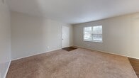 This single-floor, 2-bedroom, 2-bathroom residence at 1700 Johnson Rd in Petersburg, Virginia offers a practical and comfortable layout. The open-plan living, dining, and kitchen area serves as the heart of the home, with soft carpet underfoot in the living space and a ceiling fan overhead for year-round comfort. Natural light filters in through multiple windows fitted with blinds, creating a bright and welcoming atmosphere. The kitchen features light gray shaker-style cabinetry, a classic white subway tile backsplash, light countertops, stainless steel appliances including a dishwasher and refrigerator, and wood-look flooring that extends through the functional areas of the home. A hallway connects the main living area to the private quarters, which include two carpeted bedrooms, each with windows that allow natural light. The generously sized primary bedroom offers ample space and includes a closet. The two bathrooms are finished with clean, neutral tones; one features a tub-shower combination with white tile surround, and both include white vanity cabinetry. A dedicated utility room and additional closet storage round out the practical features of this well-organized home.