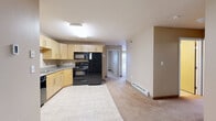 Located at 425 N 42nd St in Grand Forks, North Dakota, this two-bedroom, one-bathroom unit offers a practical and well-organized single-floor layout. The open-concept kitchen and dining area is a functional highlight, featuring light maple cabinetry with ample upper and lower storage, granite-look countertops, a double stainless steel sink, and a full suite of black appliances including a dishwasher, range, microwave, and refrigerator. Light tile flooring runs throughout the kitchen, transitioning to plush carpeting in the living and bedroom areas. The living room is generously sized, featuring a sliding glass door with vertical blinds that allows for natural light. Both bedrooms are carpeted and include windows with exterior views and baseboard heating. The primary bedroom is notably spacious and includes a ceiling fan. The full bathroom is finished with matching light cabinetry, a granite-look vanity, and tile flooring. A dedicated laundry room houses a full-size washer and dryer along with overhead shelving for additional storage. Three closets throughout the unit provide ample organization space, rounding out this functional and comfortable home.