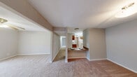 Located at 800 Valleyview Road in Pelham, Alabama, this single-floor residence offers a practical and well-organized layout across two bedrooms and three bathrooms. The open living and dining area features neutral-toned carpet throughout, creating a warm and cohesive atmosphere, while a central half-wall with a granite-style countertop bar connects the living space to the kitchen. The kitchen is outfitted with warm wood cabinetry, granite-look countertops, a double-basin sink, a dishwasher, and light tile flooring, with an adjacent pantry providing additional storage. A hallway guides residents to the private sleeping quarters, where both bedrooms are carpeted and bathed in natural light from windows with outdoor views. The primary bedroom includes a dedicated closet, while additional closet space is distributed throughout the unit. Three bathrooms serve the home, including one featuring a full tub-shower combo with built-in shelving and chrome fixtures, and another with a granite-style vanity and tile flooring. A dedicated laundry room and utility room round out the functional offerings. The overall color palette of soft beige and warm white tones lends a clean, move-in-ready ambiance throughout the space.
