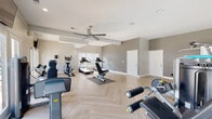 Located at 10 Gentrys Walk in Atlanta, Georgia, this fitness center offers a comprehensive and well-appointed workout facility designed to support a wide range of exercise routines. The space is laid out on a single floor and features a distinctive herringbone-patterned light wood floor that lends a polished, contemporary aesthetic throughout.

The cardio zone is equipped with multiple treadmills and elliptical machines positioned near large windows that allow ample natural light to fill the space, creating an open and energizing environment. Ceiling fans overhead provide airflow and comfort during workouts. A dedicated strength training area houses a variety of cable and weight machines, along with a full rack of dumbbells and adjustable benches to accommodate both beginners and advanced users.

Full-length wall mirrors in the strength training section enhance the sense of space while allowing users to monitor their form. Recessed lighting and neutral gray walls contribute to a clean, modern atmosphere throughout the facility. French doors along one wall open toward an outdoor pool area, connecting the interior workout space to the broader amenity offerings of the community. Wall-mounted televisions are positioned for convenient viewing during exercise. The overall design is functional, well-maintained, and thoughtfully organized to maximize usability across the entire floor plan.