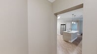 This well-appointed 990-square-foot single-floor unit offers 3 bedrooms and 3 bathrooms, designed with a clean, contemporary aesthetic. The open-concept kitchen and living area serves as the heart of the home, featuring light wood-look flooring, large windows with horizontal blinds that invite ample natural light, and a ceiling fan. The kitchen is equipped with light-toned flat-panel cabinetry, a hexagonal tile backsplash, stainless steel appliances including a range, over-the-range microwave, and refrigerator, along with a central island featuring a built-in sink, white countertops, and pendant lighting overhead. The three bedrooms are carpeted and finished in neutral warm tones, each equipped with a ceiling fan. The primary bedroom measures 180 square feet and connects directly to one of the three bathrooms. The bathrooms feature wood-look flooring, white vanities with undermount sinks, mirrors with vanity lighting, and tub-shower combos lined with white tile and built-in shelving. A hallway and closet complete the floor plan. The unit presents a cohesive, neutral color palette throughout, offering a move-in ready, functional living environment.