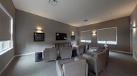 This single-floor unit offers a clean, functional layout designed for comfortable everyday living. The open living area is finished with light wood-tone luxury vinyl plank flooring that runs throughout, creating a bright and cohesive aesthetic. A ceiling fan with integrated lighting provides airflow and overhead illumination, while a skylight introduces an additional source of natural light. Clean white walls and crisp white baseboards lend a fresh, neutral backdrop throughout the space.

The kitchen is thoughtfully equipped with warm-toned wooden cabinetry, granite-style countertops, a built-in sink, dishwasher, and a full-size black refrigerator. A large window fitted with horizontal blinds allows natural light to filter into the kitchen area. The kitchen opens directly toward the living space, supporting an easy flow between the two areas. Paneled interior doors with polished hardware add a classic touch throughout the unit.

Residents also have access to a shared community lounge that features a sophisticated, contemporary design. The lounge is furnished with plush upholstered armchairs arranged around a wall-mounted flat-screen television, complemented by warm sconce lighting, framed artwork, and roller shades on the windows. The overall ambiance is polished and inviting, offering a comfortable space for relaxation or social gatherings.
