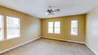 This single-floor residence offers a practical and comfortable layout across one bedroom and one bathroom. The living area is generously proportioned, featuring warm beige walls, soft wall-to-wall carpeting, and a ceiling fan with integrated lighting that ensures year-round comfort. Multiple windows allow natural light to filter throughout the space, creating a bright and welcoming atmosphere.

A pass-through window connects the living area to the kitchen, enhancing the open feel between spaces. The kitchen is outfitted with warm wood-toned cabinetry, laminate countertops, and includes a full-size refrigerator, providing ample storage and functionality.

The bedroom is a well-sized retreat with carpeted flooring, multiple windows that invite natural light, and a ceiling fan overhead. Closet access is conveniently integrated into the room.

The bathroom is thoughtfully designed, featuring a vanity with a granite-style countertop, a full-size soaking tub with a shower, and a dedicated in-unit laundry area with a full-size washer and dryer — a practical amenity that adds significant convenience. Consistent warm beige tones and clean white trim carry throughout the space, lending a cohesive and neutral aesthetic that is easy to personalize.