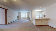 Located at 6133 Culpepper Ln in Madison, WI, this single-floor unit offers a thoughtfully arranged open-concept layout that connects the living area and kitchen in one cohesive space. The living area is generously sized, featuring neutral carpet, white walls, and a distinctive angled bay window arrangement that draws in ample natural light while providing views of the surrounding landscape. A wall-mounted air conditioning unit and baseboard heating ensure year-round comfort. An exterior door provides convenient direct access from the living area.

The kitchen is positioned adjacent to the living space and features white cabinetry extending to the ceiling, warm-toned laminate countertops, a peninsula with overhang seating, a white refrigerator, and a coil-top range with an overhead ventilation hood. Light tile flooring distinguishes the kitchen from the carpeted living areas.

The bedrooms are well-proportioned, each equipped with ceiling fans, carpet flooring, and sliding or bifold closets with wire shelving. One bedroom includes a large window with exterior views.

Two full bathrooms serve the unit, both finished with light patterned tile flooring, white vanities, large mirrors with strip lighting, and grab bars in the shower areas. One bathroom features a walk-in shower, while the other includes a tub-shower combination.