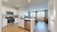 This thoughtfully designed 2-bedroom, 2-bathroom residence offers a comfortable and functional single-floor layout. The open-concept kitchen and living area serves as the heart of the home, where a sleek kitchen island with granite countertops and an integrated sink anchors the space. White shaker-style cabinetry, a full suite of stainless steel appliances — including a side-by-side refrigerator, range, built-in microwave, and dishwasher — and a subway tile backsplash complete the kitchen. Light wood-style flooring flows seamlessly throughout the entire residence, adding warmth and continuity. The living room is generously sized, bathed in natural light from large windows dressed with sheer drape panels, and features a ceiling fan overhead. The primary bedroom offers a comfortable retreat with ample natural light and access to a walk-in closet with built-in wire shelving systems. The primary bathroom includes a granite-topped vanity with white cabinetry and a tub-shower combination with marble-style tile surround. The second bathroom mirrors this clean, modern aesthetic. A second walk-in closet provides additional storage. Recessed lighting throughout enhances the bright, airy ambiance of the entire residence.