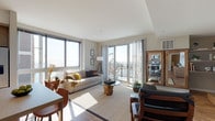 Located at 850 Pacific St in Stamford, Connecticut, this modern single-floor residence offers a thoughtfully designed open-concept layout with an abundance of natural light throughout. The living area is expansive and airy, featuring warm hardwood-style flooring, clean neutral walls, and floor-to-ceiling sliding glass doors that open onto a private balcony with sweeping panoramic views of the harbor and surrounding cityscape. The kitchen is sleek and functional, outfitted with light wood upper cabinetry, white lower cabinets, a light-toned countertop, and a full suite of stainless steel appliances including a gas range, built-in microwave, dishwasher, and refrigerator. The primary bedroom enjoys generous proportions and a large picture window framing elevated waterfront and marina views, while the second bedroom is equally well-lit with its own oversized window offering urban outlooks. The primary bathroom features a modern floating vanity, wood-look flooring, and a glass-enclosed walk-in shower, while the second bathroom offers a similar contemporary finish. Throughout the residence, consistent hardwood-style flooring, recessed lighting, and a refined neutral palette create a cohesive and polished living environment ideal for modern urban living in Stamford.
