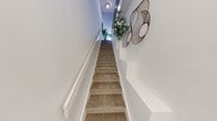 Located at 5555 North Military Trail in Boca Raton, FL, this two-bedroom, two-bathroom two-story home offers a thoughtfully designed layout spread across two levels. The main floor houses the primary living areas, including an open-concept kitchen, dining room, and living room, while the upper level accommodates the bedrooms and additional bathroom.

The kitchen is a standout feature, equipped with stainless steel appliances, dark charcoal cabinetry with a tile backsplash, and an extended granite-topped peninsula that flows into the dining and living areas. A bold teal accent wall adds a pop of color that carries through the home's design. The living room features a shiplap-paneled accent wall and durable wood-look flooring.

The carpeted staircase with white balustrades and a teal-painted stringer leads to the upper level. The primary bedroom includes an open built-in closet system and carpeted flooring. The second bedroom features a vibrant orange accent wall, a ceiling fan, and a window with natural light. Both bathrooms are finished with granite vanities, dark cabinetry, and tiled shower-tub combos with crisp white curtains. The overall aesthetic is colorful, modern, and well-appointed throughout.