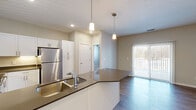 Located at 14847 Piper Lakes Circle in Grand Haven, Michigan, this well-appointed 2-bedroom, 2-bathroom unit offers a thoughtfully designed single-level layout. The open-concept kitchen serves as the heart of the home, featuring crisp white shaker cabinetry, dark quartz countertops, a full suite of stainless steel appliances including a refrigerator, range, and microwave, and a peninsula island illuminated by pendant lighting — ideal for casual dining or entertaining. The kitchen flows seamlessly into a spacious living area with hardwood-style flooring and a sliding glass door that opens to a private balcony with wooded views.

Both bedrooms are carpeted for comfort, offering a quiet retreat from the main living space. The generously sized primary bedroom includes a walk-in closet outfitted with wire shelving for organized storage. The two bathrooms are finished with white vanity cabinetry, modern fixtures, and wood-look flooring. A dedicated in-unit laundry room houses a full-size washer and dryer, adding everyday convenience. The neutral color palette and clean finishes throughout lend the space a modern, move-in-ready aesthetic suitable for a variety of lifestyles.