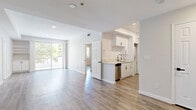 This thoughtfully designed 3-bedroom, 2-bathroom single-floor residence offers a clean, modern aesthetic throughout. Light wood-style flooring runs consistently across every room, complemented by a crisp white and soft neutral color palette that enhances the bright, airy atmosphere. Recessed lighting is featured throughout the home, adding to the well-lit interior.

The open-concept living area is generously proportioned, featuring a tray ceiling detail and direct access to a private balcony through sliding glass doors, where views of mature trees create a serene natural backdrop. The kitchen is efficiently positioned adjacent to the living space, outfitted with white shaker cabinetry, light stone countertops, a stainless steel dishwasher, and matte black hardware and fixtures.

Both bathrooms maintain a consistent modern style, featuring light wood-style flooring, white vanities with stone countertops, matte black fixtures, and tub-shower combinations. One bathroom includes a frosted glass window for natural light, while the other features a glass block window accent.

The spacious primary bedroom offers ample room and natural light through large windows with outdoor views. The two additional bedrooms are well-sized, each with windows framing greenery outside. Mirrored sliding closet doors are featured in at least one bedroom, maximizing both storage and the sense of space. Three hallways connect the layout efficiently, with an additional dedicated closet providing extra storage.