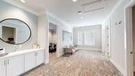 Located at 9650 52nd Ave E in Palmetto, Florida, this single-floor professional office suite offers a thoughtfully designed workspace that balances functionality with refined aesthetics. The layout includes two private offices, a dedicated conference room, and an open reception and waiting area, all finished with a cohesive, modern palette of soft neutral tones and crisp white trim.

The reception area greets visitors with comfortable seating, patterned carpeting in warm earth tones, and curated wall art, including a large abstract landscape piece that anchors the space. A built-in white cabinetry unit and a round mirror add practical elegance near the entrance. Natural light filters in through white-slatted blinds, brightening the open common areas throughout.

The conference room is equipped with a large wooden meeting table, ergonomic task chairs, a wall-mounted display screen, and generous window treatments with floor-length drapes, creating a professional yet comfortable setting for meetings. A smaller private office features a bold teal accent chair, decorative side table, and its own natural light source, lending a more intimate, boutique feel.

Additional highlights include crown molding, recessed and ceiling-mounted lighting, and a clean, open flow between spaces. The overall ambiance is polished and inviting, well-suited for a professional services or business environment.