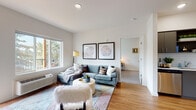 Located at 13361 SE 172nd Ave in Happy Valley, Oregon, this single-floor residence offers a thoughtfully designed open-concept layout with modern finishes throughout. The kitchen serves as a functional centerpiece, featuring slate-gray cabinetry, a classic white subway tile backsplash, light quartz countertops, and a full suite of stainless steel appliances including an electric range, microwave, and refrigerator. The kitchen flows seamlessly into the living area, which is brightened by large windows framing views of surrounding greenery, creating an inviting, airy atmosphere. Wood-style flooring extends throughout the main living spaces, adding warmth and continuity to the design.

The unit includes two bedrooms, each carpeted and outfitted with windows that allow natural light and outdoor views. The primary bedroom offers a calm, neutral palette well-suited for rest. Two full bathrooms are finished with gray vanity cabinetry, white countertops, wood-style flooring, and tub-shower combinations. Clean white walls throughout the unit lend a bright, contemporary feel, while recessed lighting provides consistent illumination. The overall design balances modern aesthetics with practical functionality, making this a well-appointed and comfortable living space.