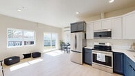 This 560 square foot apartment in Kennewick, WA, offers a thoughtfully designed living space with one bedroom and one bathroom. The interior showcases a modern aesthetic with light wood flooring throughout, creating a seamless flow between rooms. The kitchen is a standout feature, boasting a two-tone cabinet design with white upper cabinets and navy blue lower cabinets, complemented by stainless steel appliances and a subway tile backsplash. The living area is bathed in natural light from large windows, offering views of the surrounding area and providing a sense of openness. The bedroom, measuring 130 square feet, includes a built-in closet and is equipped with a mini-split air conditioning unit for comfort. The apartment also features a dedicated utility room with full-sized washer and dryer. Recessed lighting and neutral wall colors contribute to the overall bright and airy ambiance. The efficient layout maximizes the use of space, making this compact apartment feel spacious and inviting.