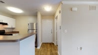 Located at 7350 Campbellton Rd in Atlanta, Georgia, this single-floor residence offers a thoughtfully designed open-concept layout that seamlessly connects the main living areas. The entryway welcomes visitors with warm wood-style flooring that continues through the kitchen and dining areas, creating a cohesive and inviting flow throughout the space.

The kitchen is a functional highlight, featuring white shaker-style cabinetry, dark wood-tone countertops, a stainless steel refrigerator, a black electric range, and an undermount sink. A peninsula with pendant lighting serves as a natural divider between the kitchen and the main living area, adding both style and practicality.

The open living area transitions from wood-style flooring to plush wall-to-wall carpeting, offering a comfortable setting enhanced by crown molding and a ceiling fan with a light fixture. Natural light filters in through windows fitted with blinds, brightening the space and offering views of the surrounding greenery.

The bedroom is generously proportioned, finished with soft carpeting, a ceiling fan, and a window that allows ample natural light. The bathroom is clean and modern, with white shaker vanity cabinetry, dark wood-tone countertops, a large mirror, and wood-look tile flooring. Textured ceilings and neutral-toned walls are consistent throughout, lending the space a warm, understated character.