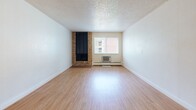 Located at 1301 30th St in Boulder, CO, this one-bedroom, one-bathroom unit offers a practical and comfortable layout across a single floor. The open-concept living, dining, and kitchen area is anchored by a striking brick fireplace, creating a warm focal point in the main living space. Light hardwood-style flooring runs throughout, complemented by a textured ceiling and bright white walls. A window unit provides climate control, and baseboard heating adds additional comfort. The galley-style kitchen is efficiently designed with warm wood cabinetry, light countertops, a double-basin sink, and stainless steel appliances including a refrigerator and electric range. A pass-through counter connects the kitchen to the living and dining area, enhancing the open feel. The bedroom features plush carpeting, a large window that frames lush greenery outside, and a spacious sliding-door closet. The bathroom includes a full tub-shower combination with a privacy window that allows natural light. Three closets throughout the unit provide ample storage. With its functional layout, classic details, and convenient Boulder location, this residence offers a well-rounded living experience.