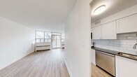 Located at 2050 Keele St in Toronto's Mount Dennis neighbourhood, this well-appointed 4-bedroom unit offers a thoughtfully designed single-floor layout with a clean, modern aesthetic throughout. Light wood laminate flooring flows seamlessly across all rooms, complemented by crisp white walls and trim that lend a bright, airy feel to the entire space.

The living room is generously proportioned, anchored by a wall of floor-to-ceiling windows and a sliding glass door that opens onto a private balcony. The outdoor space overlooks the surrounding neighbourhood, providing an open, unobstructed view. Baseboard heaters line the windowed walls, ensuring warmth throughout the seasons.

The kitchen features white shaker-style cabinetry with ample upper and lower storage, a soft blue subway tile backsplash, stainless steel appliances including a full-size refrigerator and dishwasher, and a sleek countertop — a well-equipped space for everyday cooking.

Each of the four bedrooms is finished with the same light flooring and neutral walls, offering versatility for various uses. The primary bedroom benefits from a large window with views of the outdoors. The bathroom is finished with classic white subway tile surrounding a full soaker tub and shower, paired with chrome fixtures for a clean, timeless look.