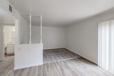 Located at 3334 W Caldwell Ave in Visalia, California, this single-floor unit offers a clean, functional layout designed for comfortable everyday living. The interior is finished in a neutral white palette throughout, creating a bright and cohesive atmosphere across all spaces.

The living area features a combination of light wood-look vinyl flooring and plush carpet, with the two zones subtly delineated by a decorative white spindle partition. A sliding glass door with vertical blinds fills the space with natural light and provides direct access to an outdoor area. The layout flows naturally into a dining or entry area, also finished with the same wood-look vinyl flooring.

The kitchen is positioned at the heart of the unit and is accessed through a half-wall pass-through opening, offering a connected feel to the main living space. It is equipped with white cabinetry, light granite-style countertops, a double stainless steel sink, a gas cooktop, and a dishwasher. A window above the sink brings in additional natural light and outdoor views.

The bathroom is well-appointed with a full tub-and-shower combination, a white vanity with matching granite-style countertops, a large mirror, and wood-look vinyl flooring, maintaining the consistent design language found throughout the unit. Ceiling vents and wall-mounted heating units ensure year-round comfort throughout the home.