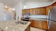 Located on N Traverse Mountain Blvd in Lehi, Utah, this well-appointed 2-bedroom, 2-bathroom single-story home offers a thoughtfully designed layout with comfortable living spaces throughout. The open kitchen and living area serves as the heart of the home, showcasing rich warm-toned cabinetry, granite countertops, stainless steel appliances including a refrigerator, range, and over-the-range microwave, and light hardwood-style flooring. Pendant lighting accents the kitchen, which flows naturally into the living area complete with a fireplace. Vaulted ceilings throughout lend an airy, expansive feel to the interior. Both bedrooms feature soft carpeting and vaulted ceilings, with the generously sized primary bedroom offering multiple windows that fill the room with natural light and views of surrounding greenery. A walk-in closet with built-in shelving and hanging rods provides ample storage. Each bathroom is finished with granite-topped vanities and warm wood cabinetry, with tub-shower combinations and light hardwood-style flooring. A dedicated laundry area includes a full-size washer and dryer. This home combines practical functionality with attractive finishes throughout.