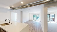Located on the fourth floor at 2144 Butler Ave in the vibrant West Los Angeles neighborhood of 90025, this modern unit offers a thoughtfully designed single-floor layout with clean, contemporary finishes throughout. The open living area features light-toned hardwood flooring, crisp white walls, and recessed lighting, creating a bright and airy atmosphere. An eye-catching exposed metal duct runs along the ceiling, adding an industrial design accent to the otherwise minimalist aesthetic. Sliding glass doors lead to a private balcony, inviting ample natural light and outdoor views into the living space. The dedicated bedroom is finished with plush carpeting and its own sliding glass door access to a balcony, offering a comfortable and serene retreat. The galley-style kitchen is equipped with stainless steel appliances, including a French door refrigerator and gas range, complemented by sleek taupe cabinetry, a white quartz countertop, and a vibrant teal tile backsplash that serves as a striking focal point. Two bathrooms are finished to a high standard — one features a large backlit mirror cabinet, a glass-enclosed walk-in shower with mosaic tile flooring, and modern matte black fixtures; the other offers a floating vanity with under-cabinet storage and a streamlined backlit mirror.