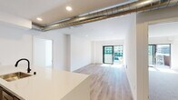 Located on the fourth floor at 2144 Butler Ave in the vibrant West Los Angeles neighborhood of 90025, this modern unit offers a thoughtfully designed single-floor layout with clean, contemporary finishes throughout. The open living area features light-toned hardwood flooring, crisp white walls, and recessed lighting, creating a bright and airy atmosphere. An eye-catching exposed metal duct runs along the ceiling, adding an industrial design accent to the otherwise minimalist aesthetic. Sliding glass doors lead to a private balcony, inviting ample natural light and outdoor views into the living space. The dedicated bedroom is finished with plush carpeting and its own sliding glass door access to a balcony, offering a comfortable and serene retreat. The galley-style kitchen is equipped with stainless steel appliances, including a French door refrigerator and gas range, complemented by sleek taupe cabinetry, a white quartz countertop, and a vibrant teal tile backsplash that serves as a striking focal point. Two bathrooms are finished to a high standard — one features a large backlit mirror cabinet, a glass-enclosed walk-in shower with mosaic tile flooring, and modern matte black fixtures; the other offers a floating vanity with under-cabinet storage and a streamlined backlit mirror.
