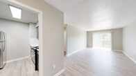 This single-floor residence offers a clean, functional layout designed for comfortable everyday living. The main living area is highlighted by light-toned wood-style flooring that runs throughout the common spaces, neutral warm-gray walls, and a large sliding glass door fitted with vertical blinds that floods the room with natural light and provides views of the surrounding greenery. A textured ceiling adds subtle character to the open living space.

The kitchen is thoughtfully appointed with gray cabinetry featuring modern hardware, crisp white quartz countertops, a classic white subway tile backsplash, a double stainless steel sink with a chrome pull-down faucet, and black appliances. The layout allows for efficient use of space and easy access to the adjoining living and dining areas.

The bedroom is comfortably finished with plush neutral carpeting, ample wall space, and a dedicated HVAC vent, ensuring year-round comfort. Built-in shelving in the hallway provides convenient storage solutions.

The bathroom includes a vanity with matching gray cabinetry and white countertop, a tiled tub-shower combination, and light wood-style flooring that ties cohesively into the rest of the space. Throughout the residence, consistent neutral tones and clean finishes create a calm, move-in-ready environment.