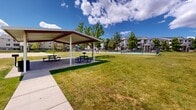 Located at 1801 W 4650 S in Roy, Utah, this well-maintained outdoor community space offers a generous and inviting environment designed for gathering and recreation. The grounds are anchored by broad, open lawns that stretch across the property, providing ample green space for relaxation and outdoor activities. Mature trees are thoughtfully distributed throughout, offering natural shade and enhancing the overall appeal of the landscape.

A standout feature of the grounds is the covered picnic pavilion, which shelters multiple picnic tables on a concrete pad — an ideal setting for community events, casual gatherings, or outdoor dining. A concrete walkway runs through the property, connecting key areas and ensuring easy accessibility across the grounds.

Beyond the pavilion, the space extends to include what appears to be a sport court and a playground area, catering to a wide range of recreational needs. The multi-building residential complex that frames the grounds features neutral-toned exteriors with stone accents, balconies, and pitched rooflines, contributing to a cohesive and established neighborhood feel. Under the expansive Utah sky, the combination of open lawn, shade trees, and community amenities creates a welcoming and functional outdoor environment for residents and visitors alike.
