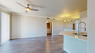 This single-floor residence is thoughtfully designed with a functional open-concept layout that connects the kitchen and living area seamlessly. The living space features wood-style plank flooring throughout, crown molding, and a ceiling fan, creating a bright and airy atmosphere. Large sliding glass doors allow ample natural light to flood the room, enhancing its open feel.

The kitchen is well-equipped with white cabinetry, light quartz-style countertops, a gray subway tile backsplash, and stainless steel appliances including a range, over-the-range microwave, and refrigerator. A peninsula with an integrated sink extends into the living area, providing additional workspace and a casual dining option.

The bedroom offers plush carpeting, a ceiling fan with a light fixture, and a window with outdoor views. It is complemented by a generously sized walk-in closet outfitted with wire shelving and hanging rods on multiple walls, offering excellent storage capacity.

The full bathroom includes a tub-shower combination, a white vanity with quartz-style countertops, chrome fixtures, and a large mirror. A dedicated in-unit laundry area houses a full-sized washer and dryer, adding everyday convenience to the overall layout.
