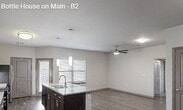 Unit 1514 at 650 S Main St is a well-appointed 2-bedroom, 2-bathroom apartment spanning 1,170 square feet on a single floor. The open-concept kitchen and living area is anchored by rich dark cabinetry, granite-look countertops, a central island with pendant lighting, black appliances, and durable wood-style plank flooring that extends throughout the main living spaces. Natural light filters in through large windows dressed with horizontal blinds. The hallway connects the living area to both bedrooms and bathrooms with a clean, efficient layout. The primary bedroom measures 210 square feet and features plush carpeting and a ceiling fan. It is complemented by a spacious walk-in closet outfitted with dual hanging rods and a built-in shelving unit for organized storage. The second bedroom also offers carpet flooring, a ceiling fan, and a window with natural light. Both bathrooms mirror the unit's cohesive design with dark cabinetry, granite-look countertops, and full tub-shower combinations with tiled surrounds. The second closet provides additional hanging and shelf storage. Neutral gray tones throughout create a modern, move-in-ready atmosphere suited for comfortable everyday living.
