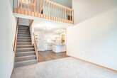 Located at 1034 N High Point Rd in Madison, WI, this two-story, two-bedroom, three-bathroom home offers a well-organized layout across two floors. The main level features a combination of hardwood-style flooring and plush carpeting, with an open living area bathed in natural light from a sliding glass door that leads to an outdoor space. A built-in closet, a full bathroom with a vanity and tile flooring, and a dedicated laundry area with side-by-side washer and dryer complete the first floor. A carpeted staircase with warm wood railings and balusters connects the two levels, opening to an airy upper hallway with a skylight and open railing overlooking the stairwell. The expansive primary bedroom occupies a generous portion of the upper floor and features vaulted ceilings, a ceiling fan, a large walk-in closet outfitted with built-in shelving and hanging rods, and a private en-suite bathroom with a sliding glass shower enclosure. A second bedroom and additional bathroom are also situated on the upper floor. Throughout the home, warm wood trim, neutral tones, and track lighting contribute to a clean, functional aesthetic well-suited for comfortable everyday living.