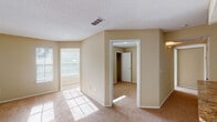 This single-story space is designed with a practical, comfortable layout that makes efficient use of its footprint. The living area is generously sized, featuring neutral beige walls, soft wall-to-wall carpeting, and multiple windows that invite an abundance of natural light, creating a warm and inviting atmosphere. A ceiling fan adds both functionality and character to one of the rooms, while a separate bedroom area offers privacy and includes access to a closet with built-in shelving.

The kitchen is well-appointed with crisp white cabinetry, granite-style countertops, and white appliances including a refrigerator, electric range, and built-in range hood. Wood-style flooring runs throughout the kitchen, complementing the cabinetry and countertops for a cohesive aesthetic.

The bathroom features a wide vanity with white cabinetry, granite-style countertops, a large mirror, and a shower-tub combination. Wood-style flooring continues here, adding consistency throughout the space.

Throughout the unit, textured ceilings, white trim, and a neutral color palette create a clean, cohesive look. The layout flows logically between the living, sleeping, and utility areas, offering a functional and comfortable living environment.