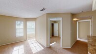 This single-story space is designed with a practical, comfortable layout that makes efficient use of its footprint. The living area is generously sized, featuring neutral beige walls, soft wall-to-wall carpeting, and multiple windows that invite an abundance of natural light, creating a warm and inviting atmosphere. A ceiling fan adds both functionality and character to one of the rooms, while a separate bedroom area offers privacy and includes access to a closet with built-in shelving.

The kitchen is well-appointed with crisp white cabinetry, granite-style countertops, and white appliances including a refrigerator, electric range, and built-in range hood. Wood-style flooring runs throughout the kitchen, complementing the cabinetry and countertops for a cohesive aesthetic.

The bathroom features a wide vanity with white cabinetry, granite-style countertops, a large mirror, and a shower-tub combination. Wood-style flooring continues here, adding consistency throughout the space.

Throughout the unit, textured ceilings, white trim, and a neutral color palette create a clean, cohesive look. The layout flows logically between the living, sleeping, and utility areas, offering a functional and comfortable living environment.