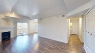 Located at 1300 S Willow St in Denver, CO, this well-appointed 2-bedroom, 2-bathroom single-floor home offers a thoughtfully designed layout with a bright, open feel throughout. The combined kitchen and living area serves as the heart of the home, showcasing hardwood-style flooring, vaulted tray ceilings, and a fireplace set into an elegant arched niche. Sliding glass doors flood the living space with natural light and provide direct access to a private balcony. The kitchen is fitted with white cabinetry, granite countertops, a tile backsplash, stainless steel appliances including a refrigerator, range, microwave, and dishwasher, and a window overlooking the exterior. Both bedrooms feature plush carpeting and generous closet space, with the primary bedroom offering a spacious walk-in closet with built-in shelving and hanging rods. The bathrooms include granite-topped vanities and tiled tub-shower combinations. A hallway connects the rooms seamlessly, and in-unit laundry is conveniently accessible off the main living area. Clean white walls and neutral finishes throughout create a bright, move-in-ready atmosphere.