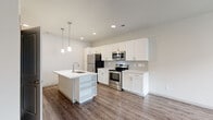 This two-story home offers 3 bedrooms and 3 bathrooms thoughtfully distributed across two floors. The main level features an open-concept kitchen and living area with durable wood-look flooring, recessed lighting, and pendant lights above a central island with a built-in sink and open shelving. White shaker-style cabinetry, a subway tile backsplash, and a full suite of stainless steel appliances complete the kitchen. An attached garage with an automatic opener provides convenient parking and additional storage. Upstairs, the upper level houses the bedrooms and remaining bathrooms. The primary bedroom offers a generous layout with plush carpeting, and an en suite bathroom featuring a glass-enclosed walk-in shower, dual-sink vanity with white cabinetry, and wood-look flooring. Additional bedrooms include carpeted or wood-look flooring and windows that bring in natural light and neighborhood views. A secondary bathroom offers a soaking tub with subway tile surround and matching white vanity. A dedicated laundry room with a full-size washer and dryer adds everyday convenience. Clean white walls, neutral tones, and consistent modern finishes create a cohesive and functional living environment throughout.